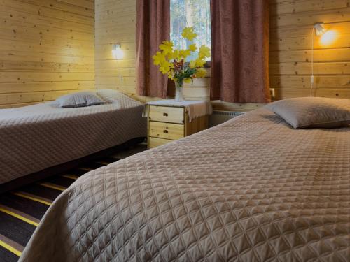 a bedroom with two beds and a vase of flowers at Villa Hauki, Puruvesi Lakeside by Naaranlahti in Naaranlahti