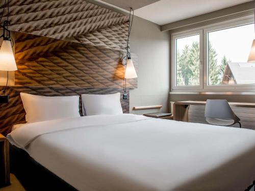 a hotel room with a large bed and two windows at ibis Zurich Adliswil in Zurich