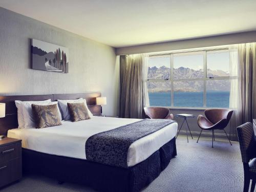 a hotel room with a bed and a large window at Mercure Queenstown Resort in Queenstown