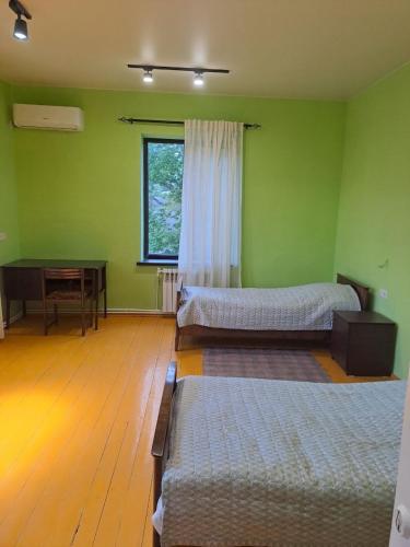 a green room with two beds and a table at Tapan in Berd
