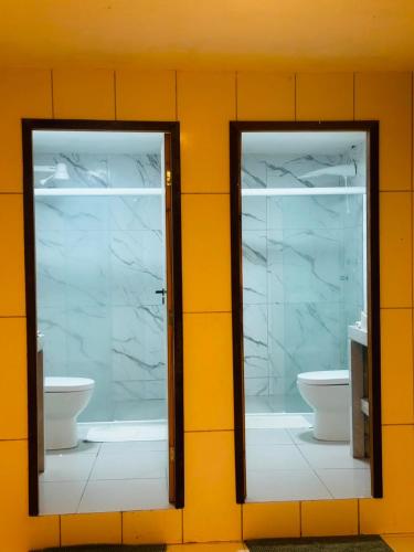 two mirrors on a wall with two sinks and a toilet at HOTEL FÊNIX in Campina Grande