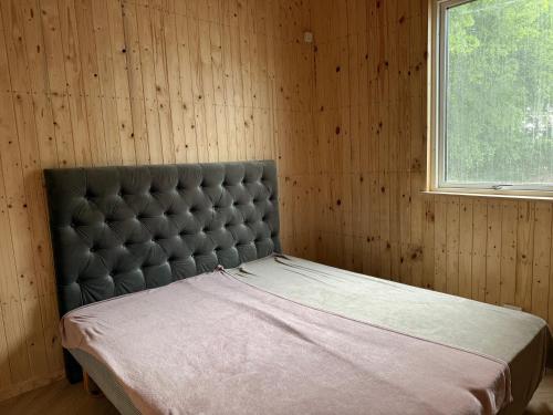 a bed in a wooden room with a window at Bornholm Eco Suites in Klemensker