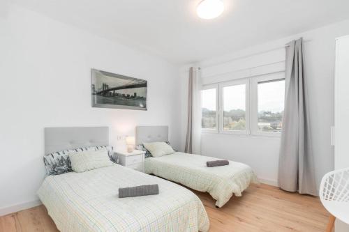 two beds in a white room with a window at Apartamento La Salamandra in Arriondas