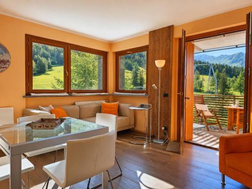 a living room with a table and chairs and a balcony at Hostdomus - Suite Les Etoiles in Sestriere
