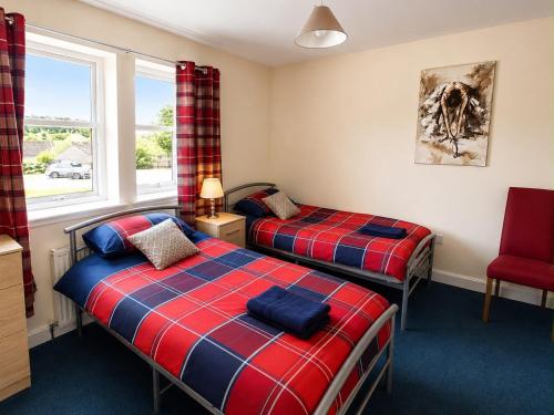 two twin beds in a room with a window at Morlich Guesthouse in Dingwall