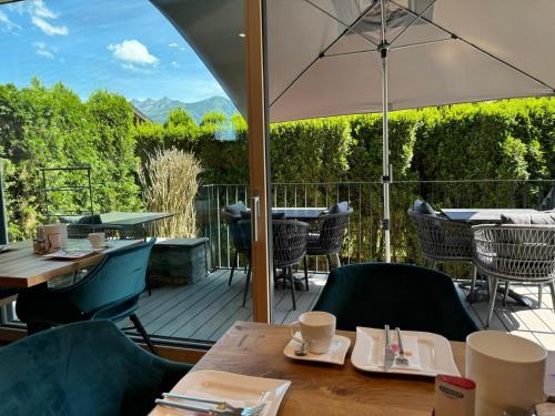 a patio with tables and chairs and an umbrella at Comfort Hotel Garni Landhaus Gitti in Zell am See