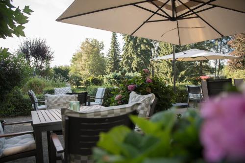 a patio with tables and chairs and an umbrella at Hotel Wilhelmshöhe Auderath in Auderath