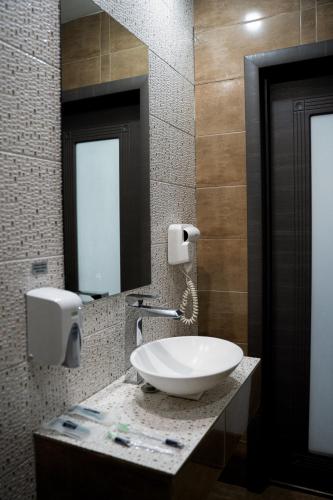 a bathroom with a sink and two mirrors at Astra City Hotel in Almaty