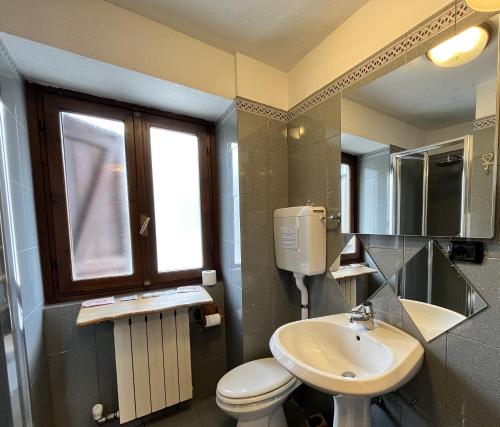 a bathroom with a toilet and a sink and a window at Hotel PIAN DEL SOLE Claviere in Claviere