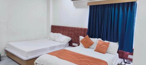 two beds in a room with blue curtains at Hotel Radhe Inn in Gandhinagar