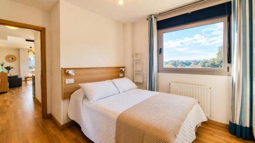 a bedroom with a bed and a large window at El Arcin - Piscina, terraza y parking en Llanes in Llanes