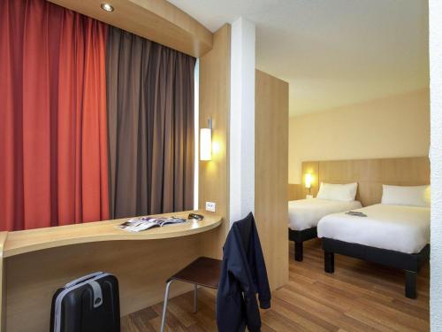 a hotel room with a bed and a desk and a bed and a room at Ibis Cavaillon Portes du Luberon in Cavaillon