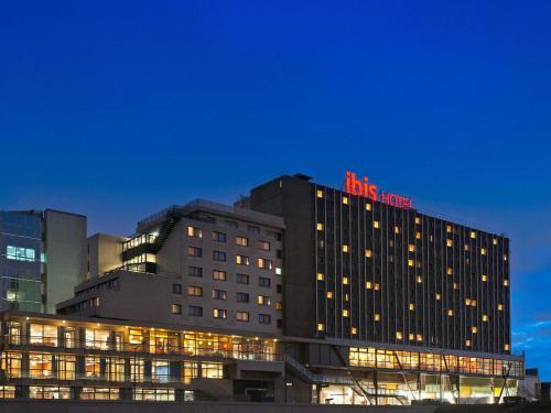 a building with a red sign on top of it at ibis Paris 17 Clichy-Batignolles in Paris