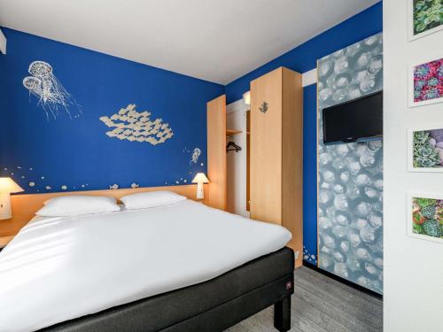a bedroom with a bed and a blue wall at ibis Luebeck City in Lübeck