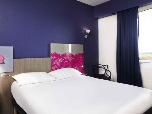 a bedroom with a white bed and a purple wall at ibis Styles Arles Palais des Congrès in Arles