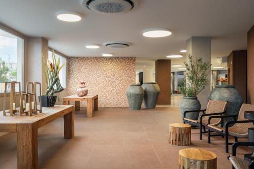 a lobby with vases and wooden tables and chairs at ALEGRIA El Mar & Spa 4 SUP in Santa Susanna