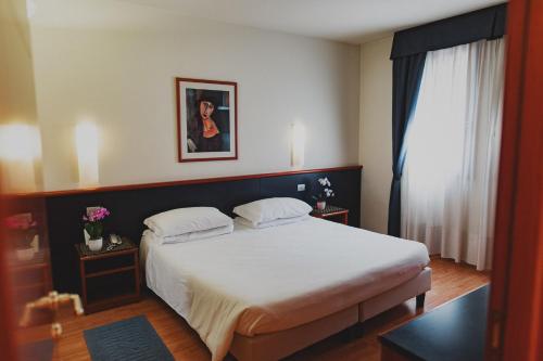 a bedroom with a large bed with white sheets at Hotel Crystal in Preganziol