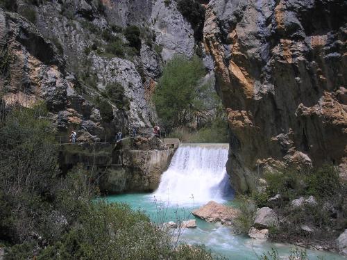 a waterfall in a canyon with people standing on a bridge at Hostería de Guara in Bierge