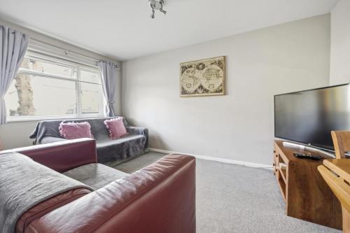 a living room with a couch and a flat screen tv at Saint Johns Rest in Biggleswade