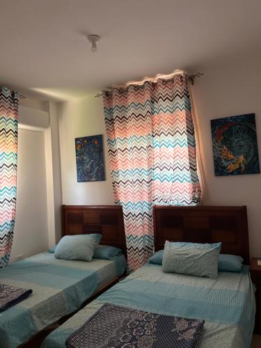 two twin beds in a room with a window at Chalet in La mera north coast in Zāwiyat al ‘Awwāmah