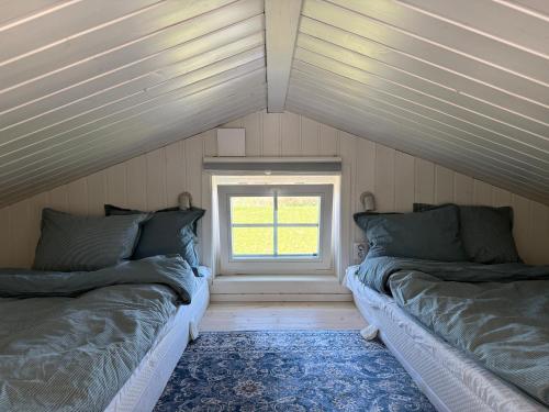 two beds in a room with a window at Minihus i lantlig miljö nära havet in Smygehamn