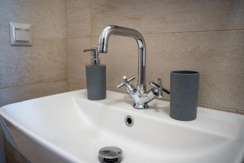 a sink with a faucet and two cups on it at Kleopatra's Apartments in Chios