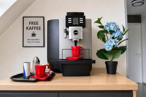 a coffee machine on a counter with red cups and a flower at Moderne Appartement in Nuremberg