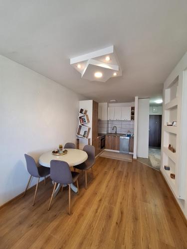 a living room with a table and chairs and a kitchen at Apartment Stup Sarajevo in Sarajevo