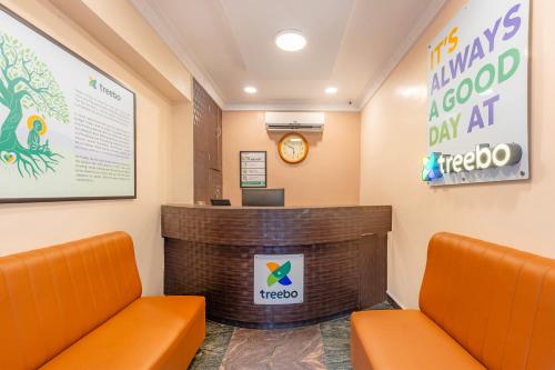 a waiting room with orange chairs and a reception desk at Treebo Golden Sun Inn, 5 Mins To Rock Beach in Pondicherry