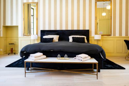 a bedroom with a large bed and a coffee table at La suite Isabelle de Luxembourg in Béthune