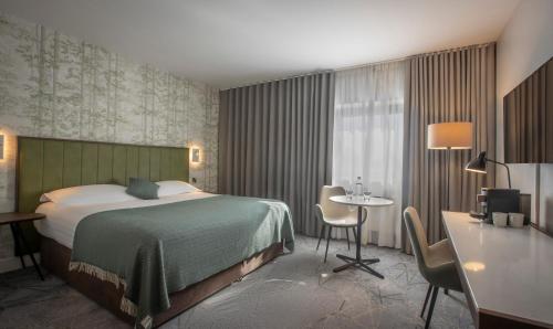 a hotel room with a bed and a desk and a table at Hoban Hotel Kilkenny in Kilkenny