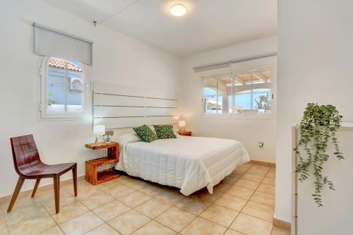 a bedroom with a bed and a chair and two windows at Refugio del Viento in Antigua