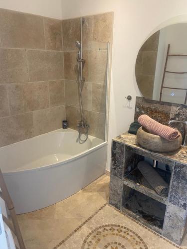 a bathroom with a tub and a shower and a mirror at Gîte chez l'habitant indépendant "La villa des ocres" in Gargas