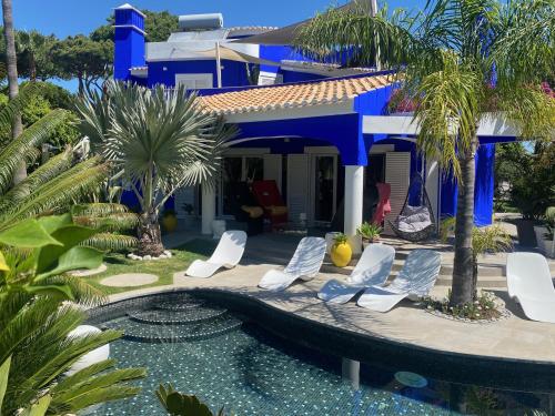 a blue house with white chairs and a swimming pool at Villa Karolina in Quarteira
