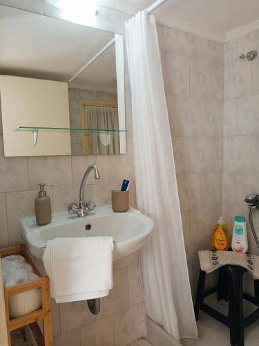 a bathroom with a sink and a shower curtain at Feidiou 1 vol II in Egina