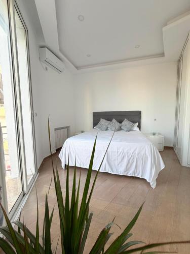 a white bedroom with a bed and a plant at Emeraude in Tunis