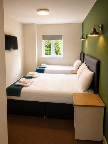 two beds in a small room with a window at Liberal House Tamworth in Tamworth