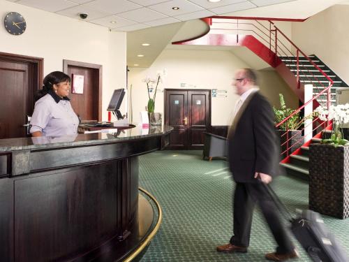 a man in a suit walking past a reception desk at ibis Hotel Brussels Expo Atomium in Brussels