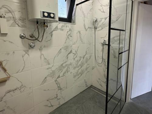 a bathroom with a shower with marble tiles at Laganini house Vinča in Belgrade