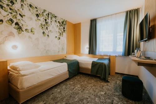a hotel room with two beds and a window at Hotel O3zone - Mountain Spa & Conference in Băile Tuşnad