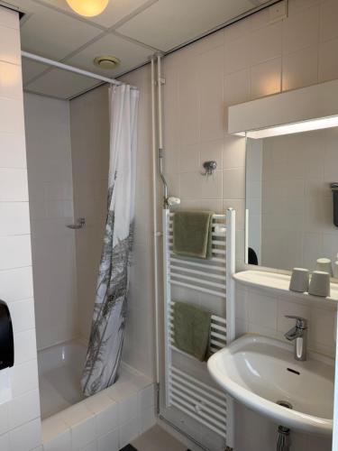 a white bathroom with a shower and a sink at Hotel Willemstad - kleinschalig hotel in Willemstad