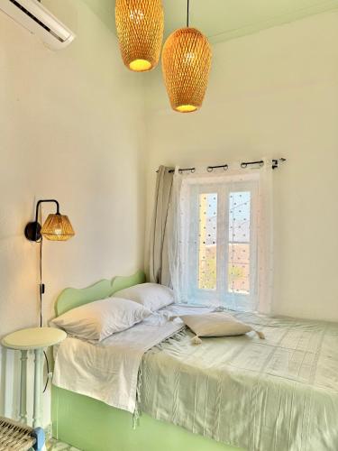 a bedroom with a bed with two lamps and a window at Villa Kastrouna, with private heated jacuzzi in Symi