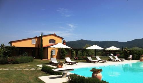 a pool with chairs and umbrellas next to a house at La Cascina nel Roseto in Rigutino