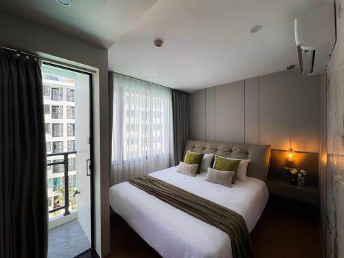 a bedroom with a large white bed and a window at Stylish Pool View 1BDR Apartment Bang Tao in Ban Thalat Choeng Thale