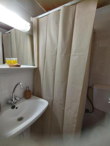 a bathroom with a sink and a shower curtain at MMrooms Μονά κρεβάτια 2ος όροφος in Tinos