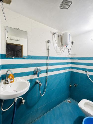 a blue and white bathroom with a sink and a shower at Hotel Shreeji Palace - OPP Hanuman Garhi Mandir in Ayodhya