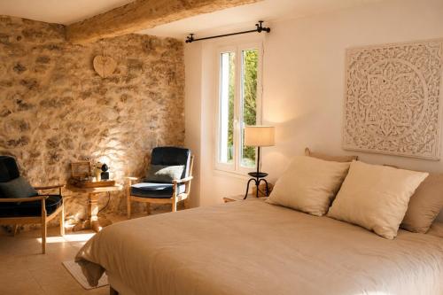 a bedroom with a bed and a window and chairs at Le Mas des Chènes in Taradeau