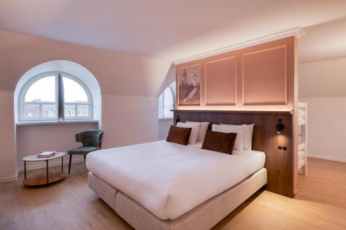a bedroom with a large bed and an arched window at Golden Tulip Hotel de’ Medici in Bruges