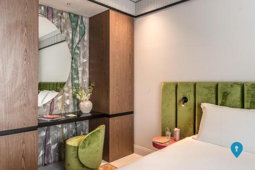 a bedroom with a bed and a green chair at TriplyRooms Collection - Roma Prassede in Rome