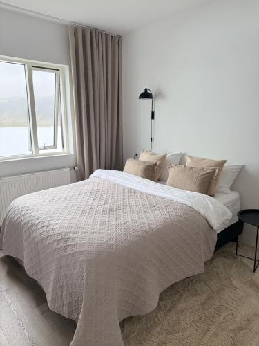 a white bedroom with a large bed with a window at New Modern Two bedroom Apartment in Hveragerði